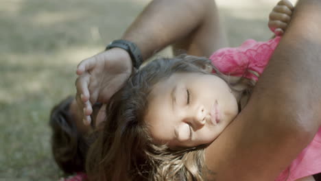 Close-up-of-sleeping-girl-lying-with-dad-on-lawn